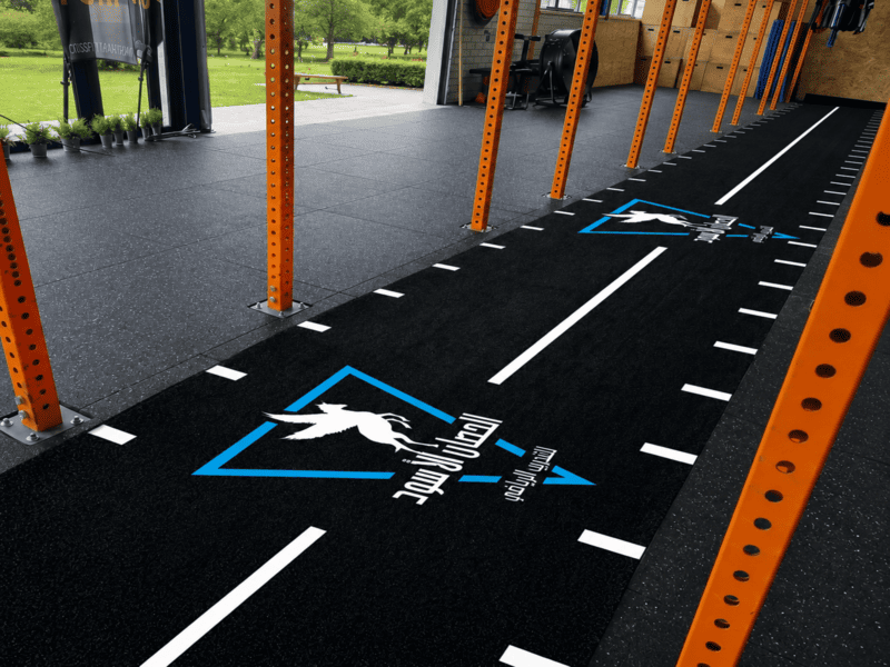 Gym owner brushing indoor turf track with a nylon broom